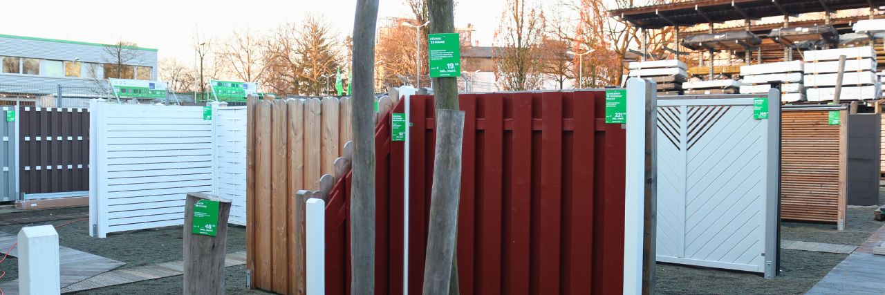 Im Vordergrund stehen viele verschiedene, bunte Gartenzäune