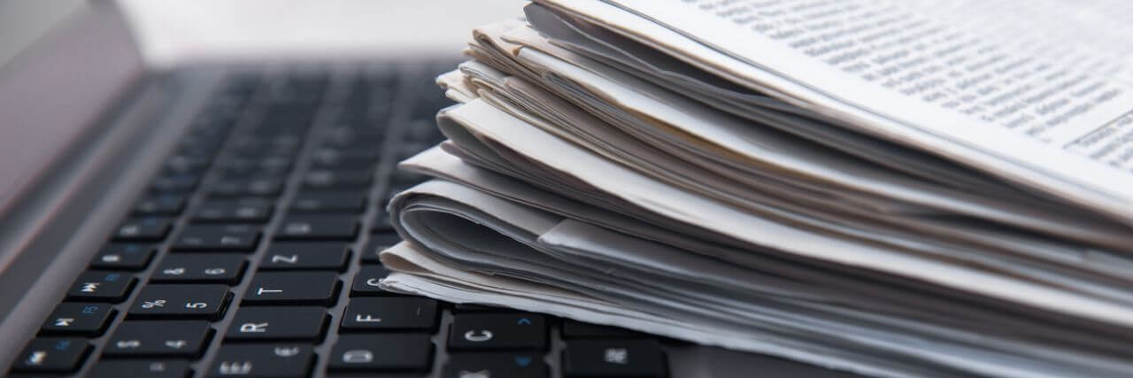 Ein Stapel Zeitungen liegt auf einer Laptop-Tastatur