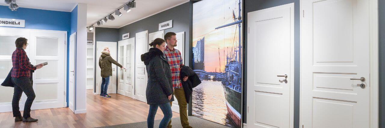 Menschen schauen sich weiße Profiltüren in der A&J Türenausstellung an